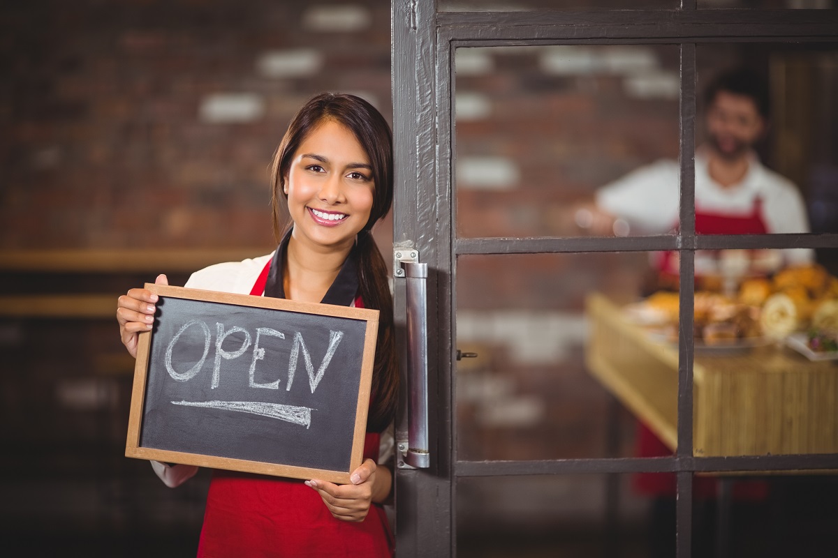 Picture of woman holding chalkboard sign with open/